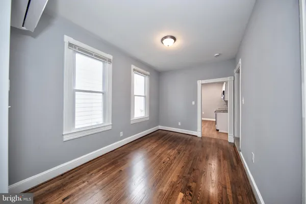 an empty room with wooden floor and windows