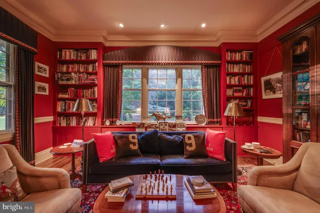 a living room with furniture a bookshelf and a large window