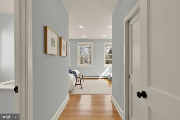 a view of a hallway with wooden floor and a bathroom