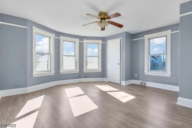 a view of an empty room with a window and wooden floor