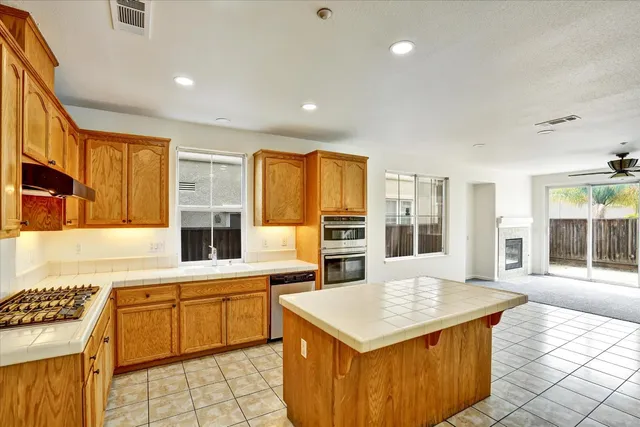 a kitchen with stainless steel appliances a stove top oven a sink a counter top space and cabinets