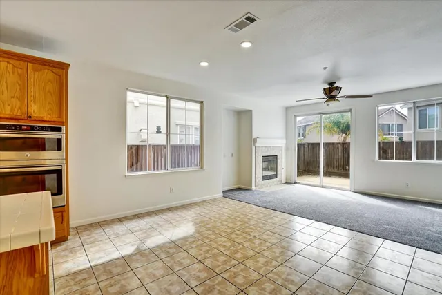 a view of a livingroom with a fireplace a ceiling fan and window