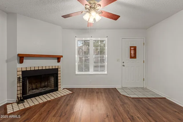 a view of empty room with wooden floor fan and a fireplace