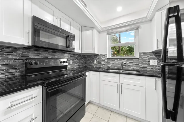 a kitchen with white cabinets and appliances