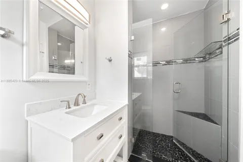 a bathroom with a sink a mirror a vanity and a shower