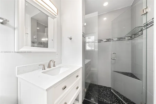 a bathroom with a sink a mirror a vanity and a shower