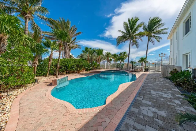 a view of a swimming pool with a garden and palm trees