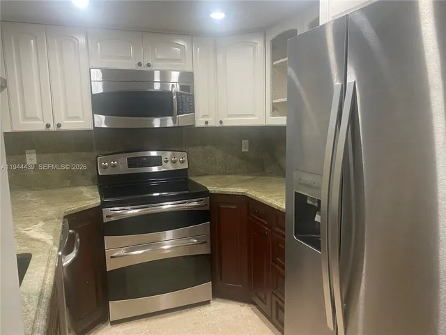 a metallic refrigerator freezer sitting inside of a kitchen