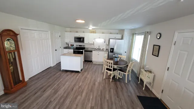 a kitchen with a table chairs refrigerator and wooden floor