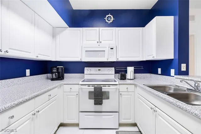a kitchen with granite countertop a sink a stove and cabinets