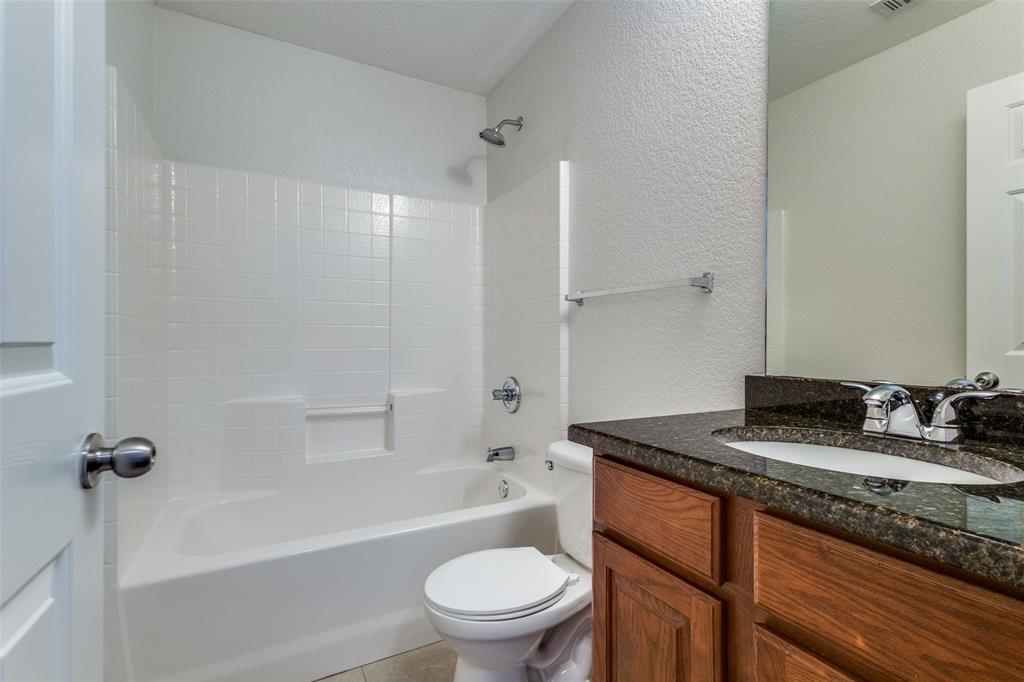 1257 Barrel Run Fort Worth, TX 76052 - Photo 17 of 26 Full bathroom featuring a white tub and shower combination with tile surround, vanity with wood-finish cabinetry, granite countertop