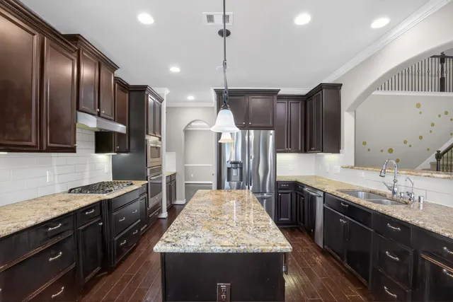 a large kitchen with stainless steel appliances granite countertop plenty wooden cabinets counter space a sink and a center island