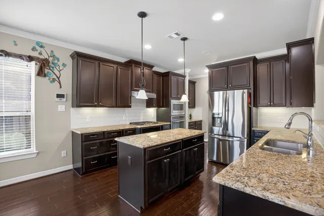 a kitchen with kitchen island granite countertop stainless steel appliances a sink stove and refrigerator