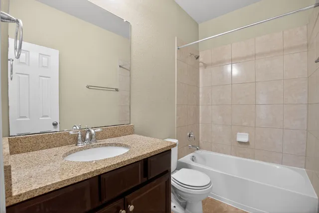 a bathroom with a granite countertop sink a toilet and shower