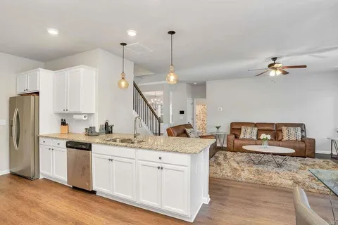 a kitchen with stainless steel appliances kitchen island granite countertop a sink a stove a refrigerator and island with wooden floor