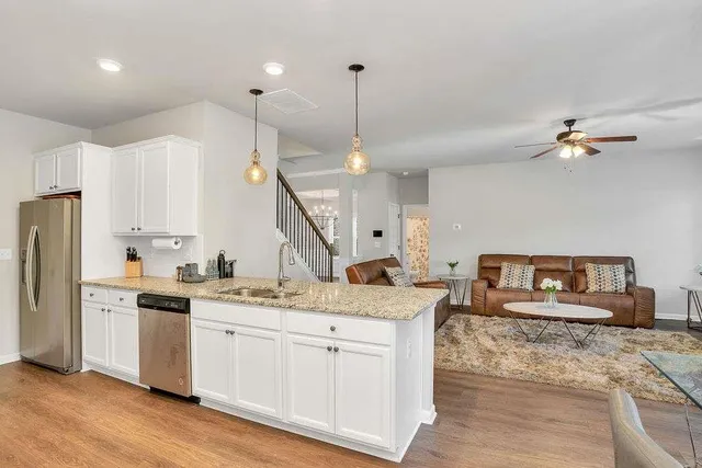 a kitchen with stainless steel appliances kitchen island granite countertop a sink a stove a refrigerator and island with wooden floor