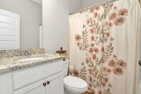 a bathroom with a granite countertop sink a toilet and a shower curtain