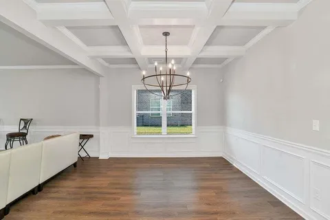 a view of empty room with wooden floor and chandelier