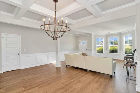 a living room with couches chandelier cabinets and wooden floor
