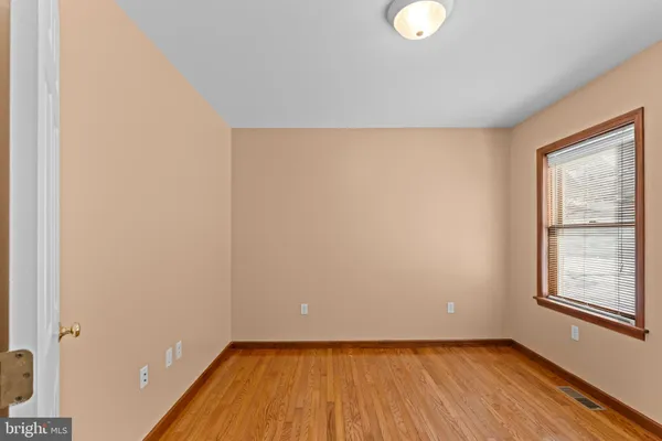 an empty room with chandelier fan and windows
