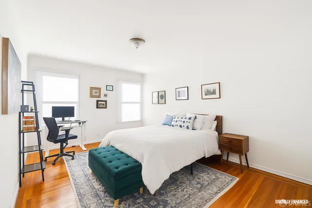 a bedroom with a bed a chair and a potted plant on the dresser