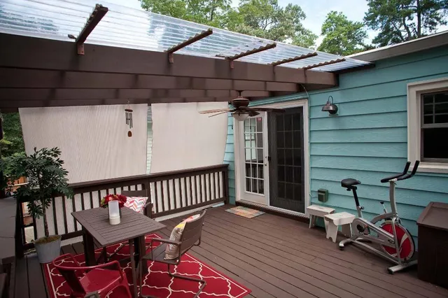 a view of a patio with table and chairs with wooden floor and fence