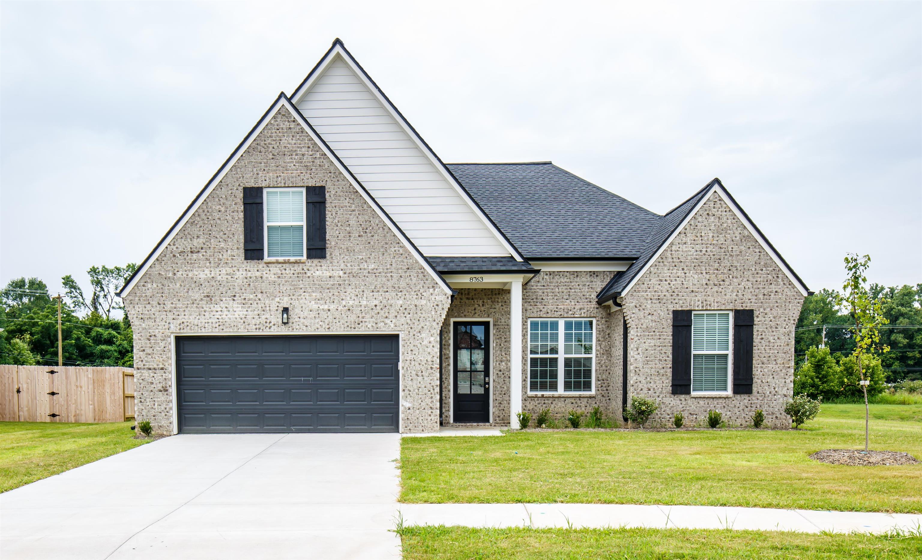 8763 Shipp Road Millington, TN 38053 - Photo 1 of 9 View of front facade with concrete driveway, a front lawn, a shingled roof, fence, and brick siding