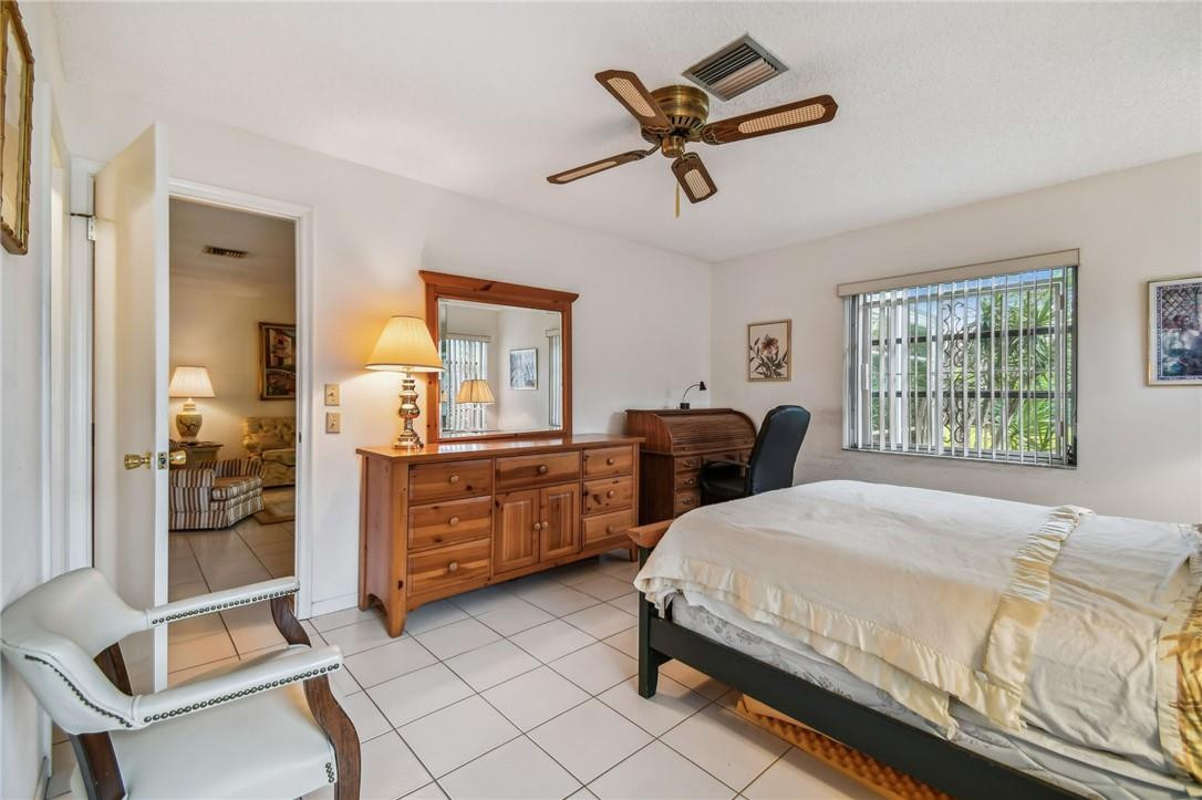 5348 Privet Place, Unit D Delray Beach, FL 33484 - Photo 30 of 60 a spacious bedroom with a bed a chandelier and dresser