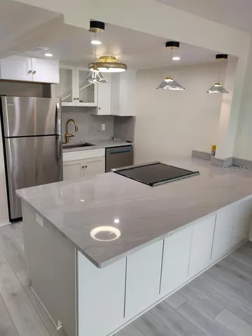 a kitchen with stainless steel appliances granite countertop a sink a refrigerator and a granite counter tops