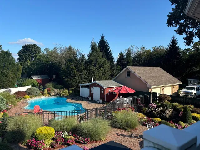 a view of swimming pool with lawn chairs under an umbrella