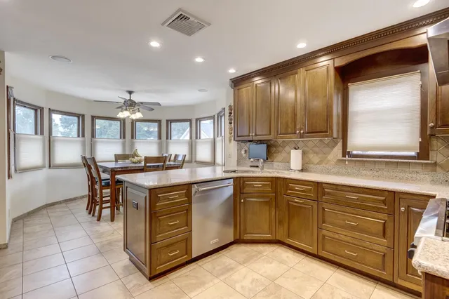 a kitchen with kitchen island granite countertop wooden cabinets a sink and appliances