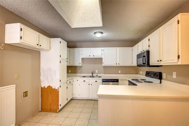 a kitchen with stainless steel appliances a refrigerator a stove a sink dishwasher and white cabinets with wooden floor