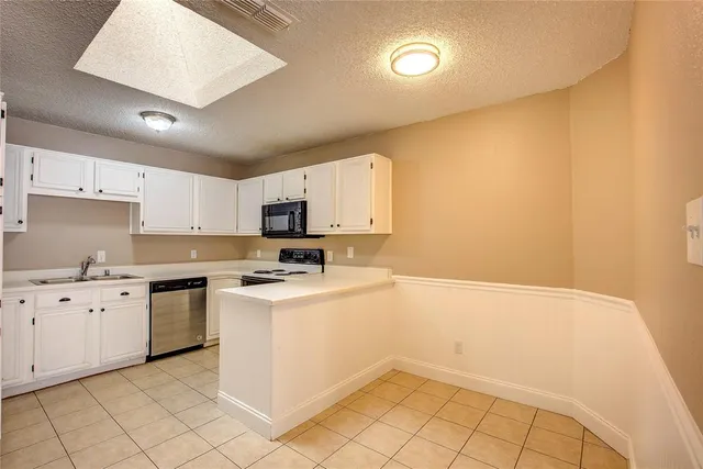 a kitchen with granite countertop a sink a stove top oven and white stainless steel appliances