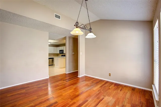 a view of empty room with wooden floor and windows