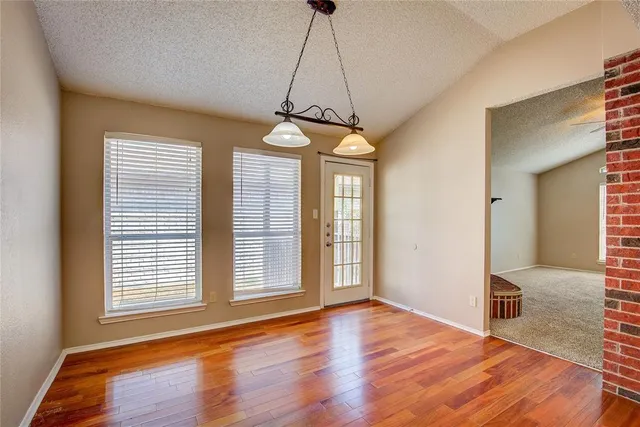 a view of a room with wooden floor chandeliers and kitchen view