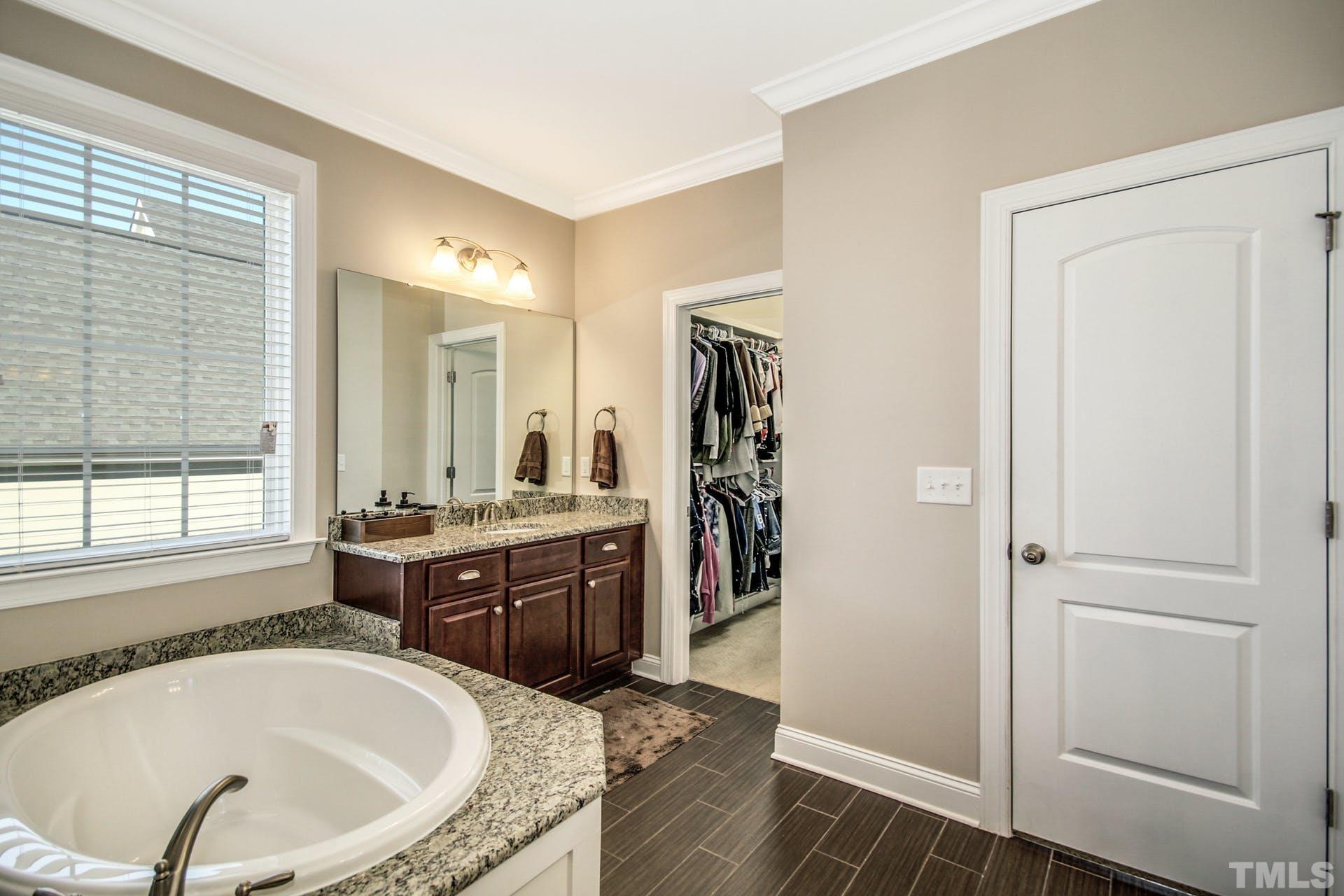 2013 White Rocks Road Wake Forest, NC 27587 - Photo 20 of 36 a bathroom with a tub a sink and a large mirror