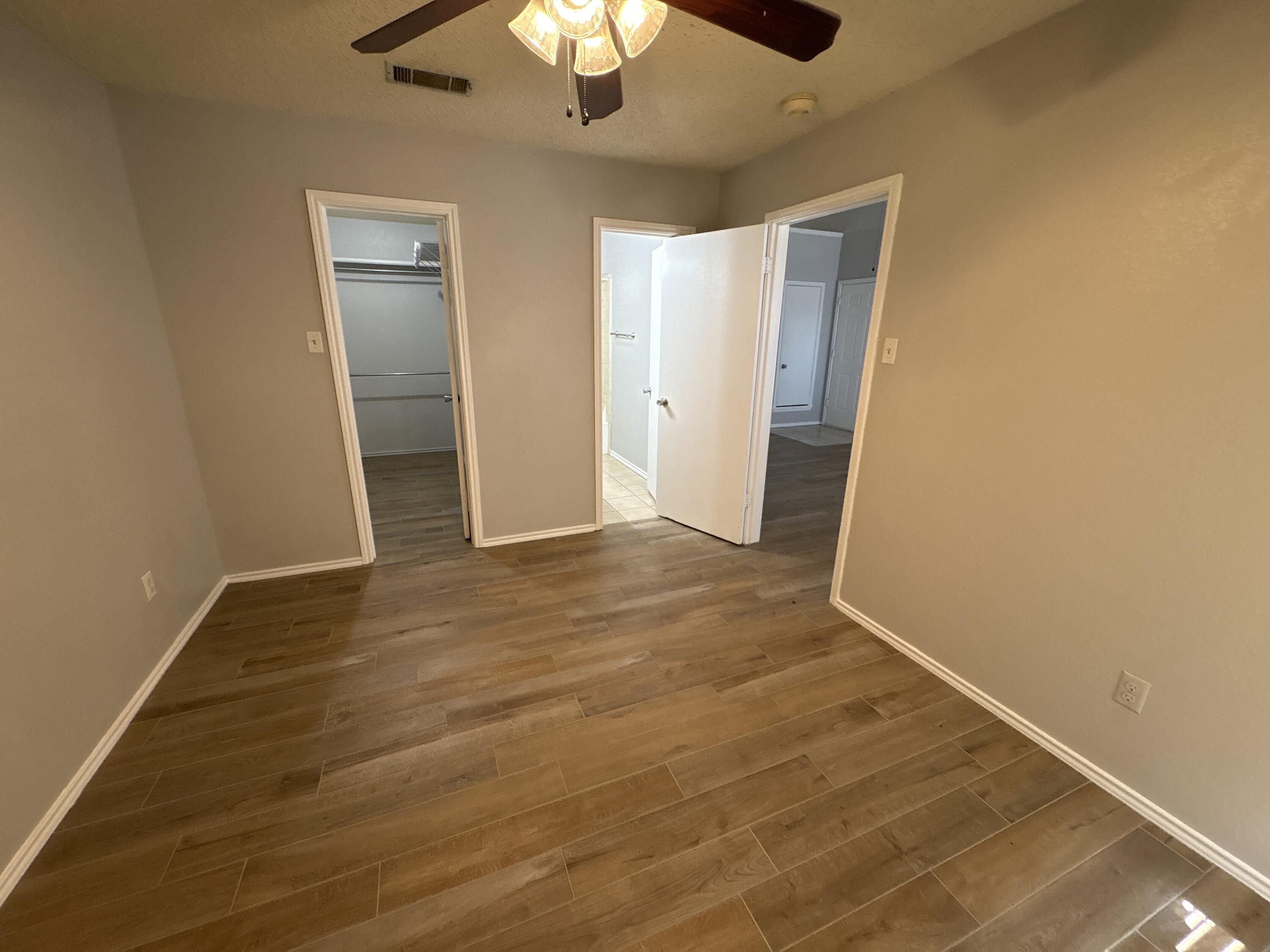 3421 Hyden Avenue Lubbock, TX 79407 - Photo 12 of 18 an empty room with wooden floor closet and chandelier fan