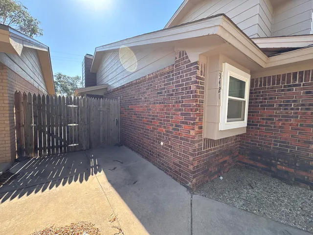 a view of backyard with brick wall and potted plants