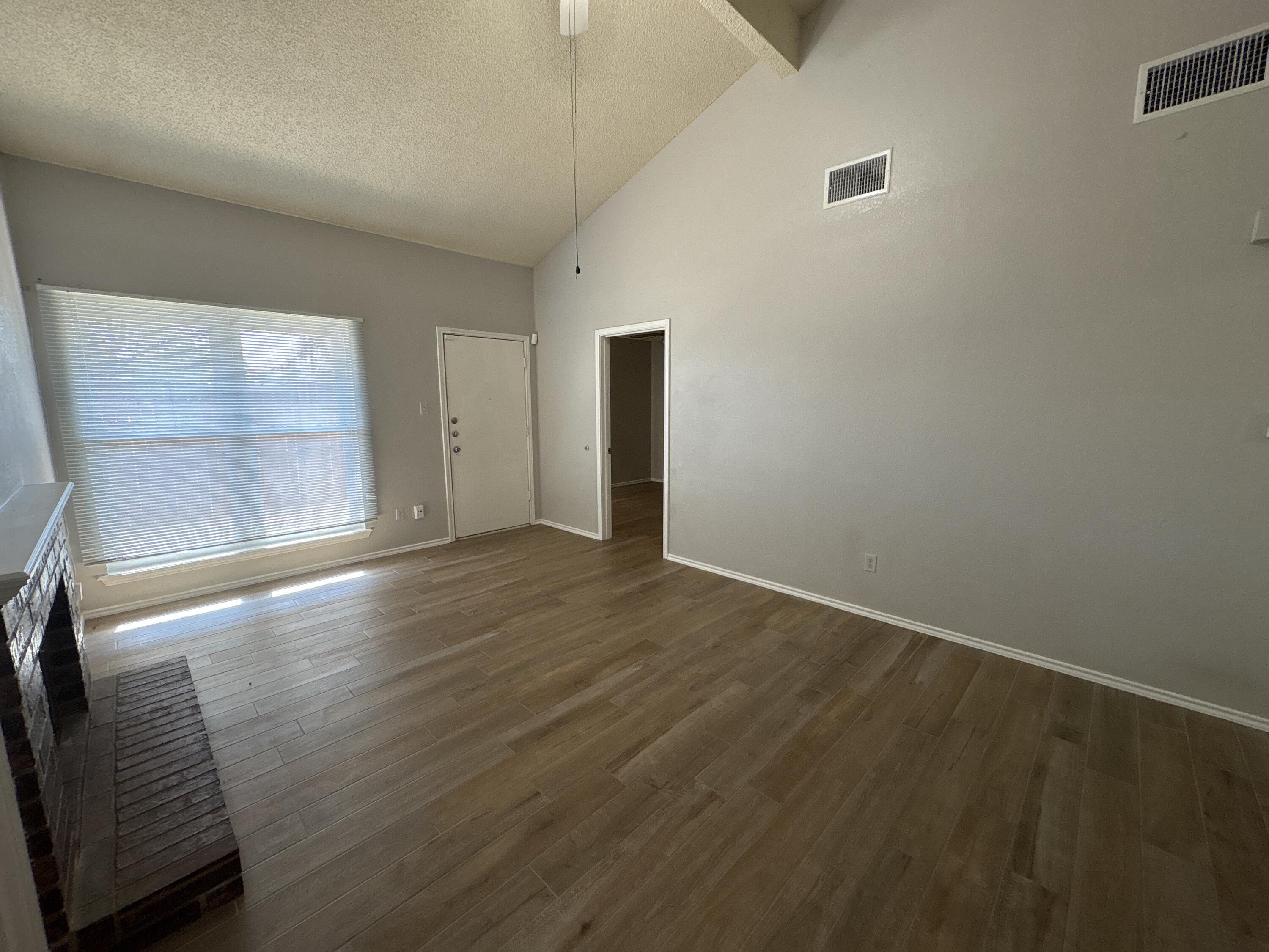 3421 Hyden Avenue Lubbock, TX 79407 - Photo 3 of 18 an empty room with wooden floor and windows