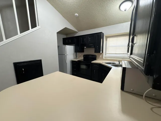 a kitchen with granite countertop a sink a stove top oven a refrigerator and blue cabinets