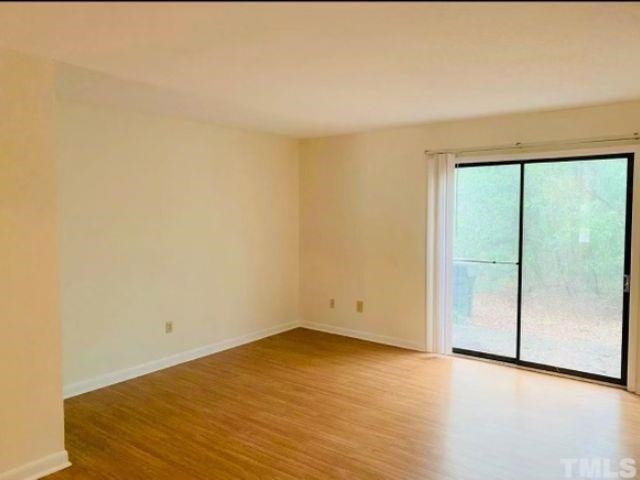 2104 Spring Forest Road, Unit 2104 Raleigh, NC 27615 - Photo 4 of 9 an empty room with wooden floor and sliding door