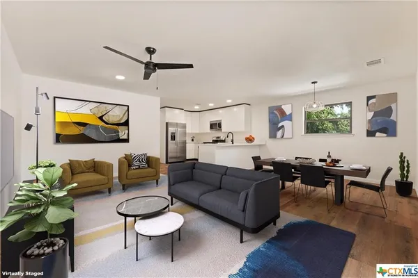 a living room with furniture kitchen view and a wooden floor