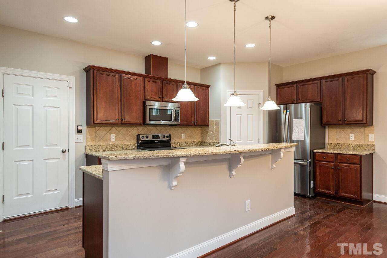 524 Bouree Circle Raleigh, NC 27606 - Photo 13 of 34 a kitchen with stainless steel appliances a sink a stove a refrigerator cabinets and wooden floor