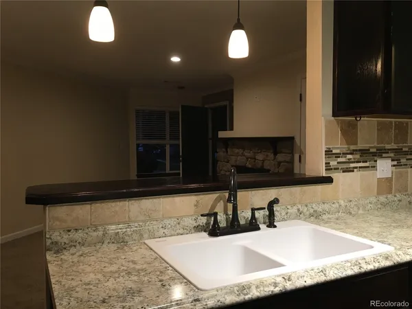 a kitchen with granite countertop a sink a counter top space and cabinets