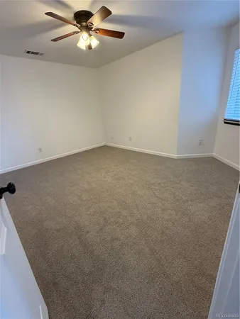 en empty room with windows and ceiling fan