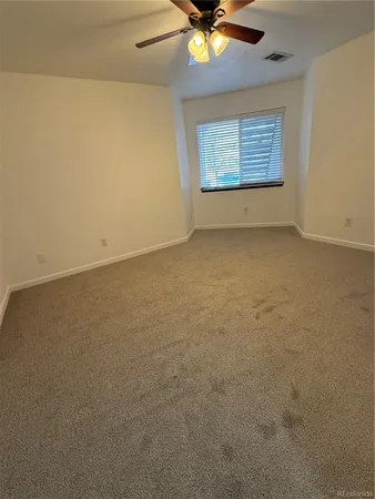 an empty room with a ceiling fan and window