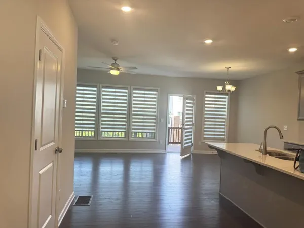 a large kitchen with stainless steel appliances kitchen island granite countertop a stove a sink a refrigerator and white cabinets with wooden floor