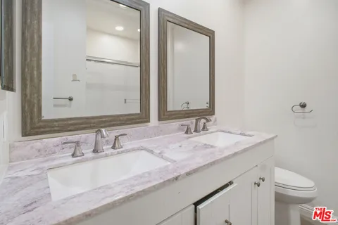 a bathroom with a granite countertop sink a toilet and a mirror