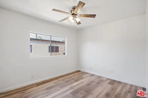 a view of a room with wooden floor and a ceiling fan