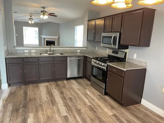 a kitchen with stainless steel appliances granite countertop a stove a sink dishwasher and a microwave oven with cabinets